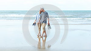 Asian Lifestyle senior couple walking chill on the beach happy in love romantic and relax time after retirement.Â 